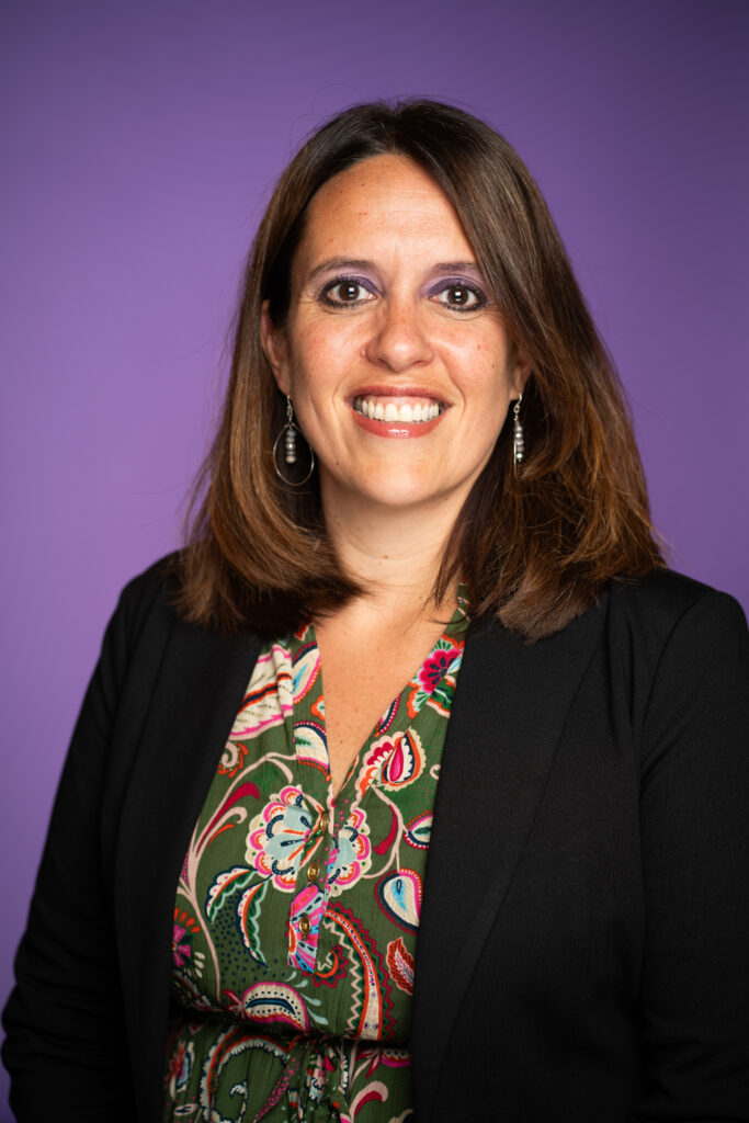Kira Foley-Tuzman - A woman in professional attire in front of a purple background